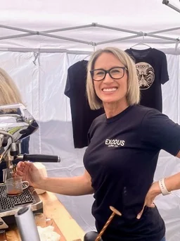 Tonya smiling behind the Exodus Coffee cart at an event